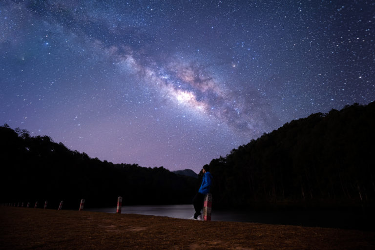 Happiness Asian man standing with beautiful night sky with stars and milky way at Pang Oung, Mae Hong Son, Thailand. Landscape Milky Way